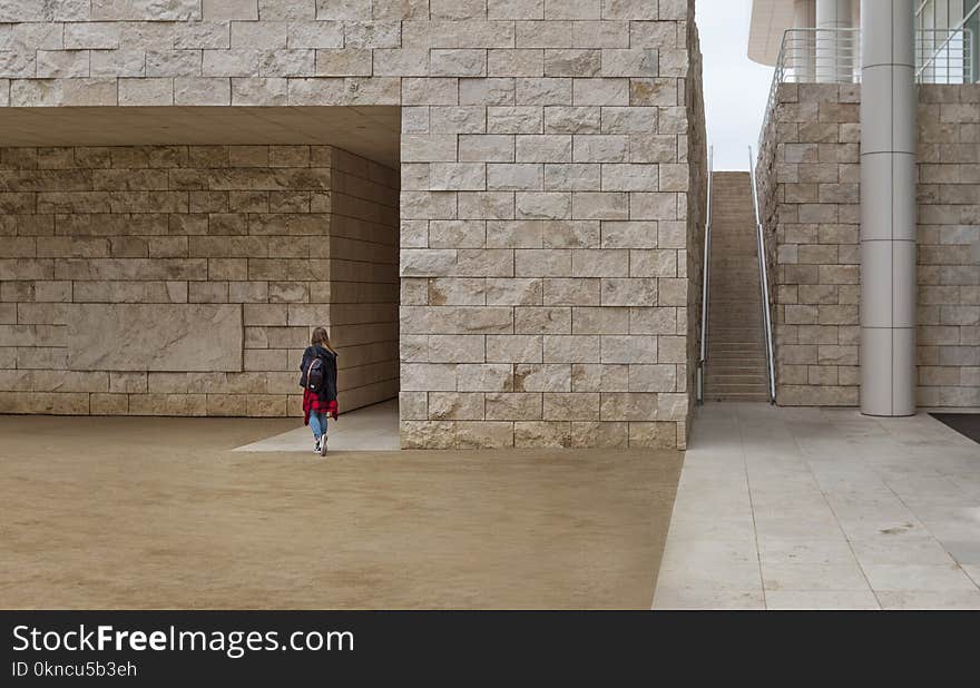 Woman Walking Near Brick Building