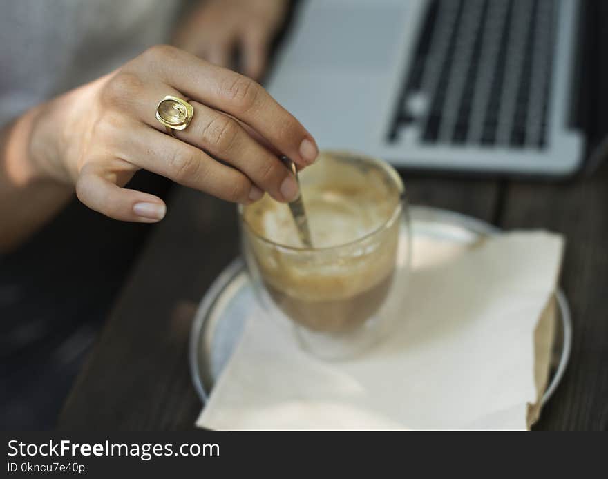 Person Holding Gray Stirrer on Clear Drinking Glass