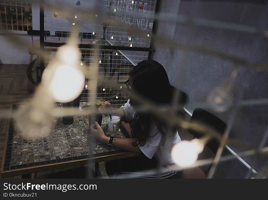 Woman Wearing White Shirt Sitting on Chair Beside Table