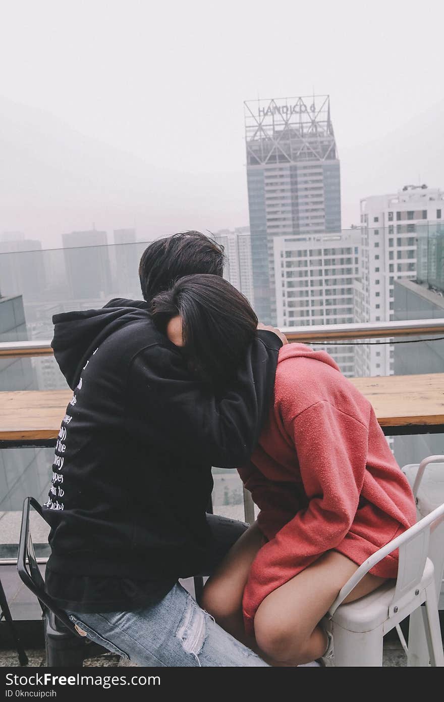 Man Hugging Woman Sitting on Chair