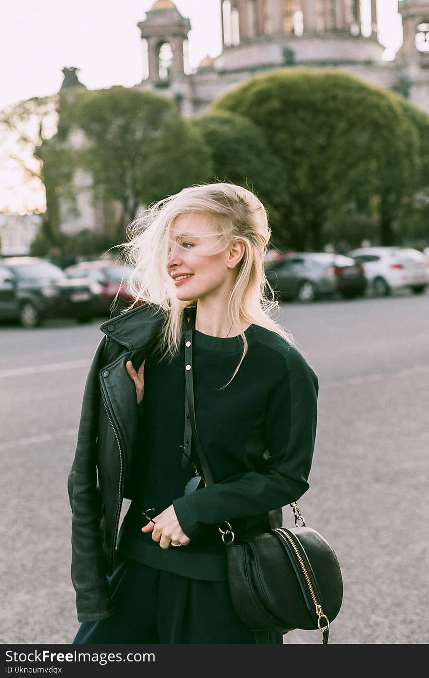 Woman Wearing Leather Jacket and Carrying Bag at the Parking Lot during Day