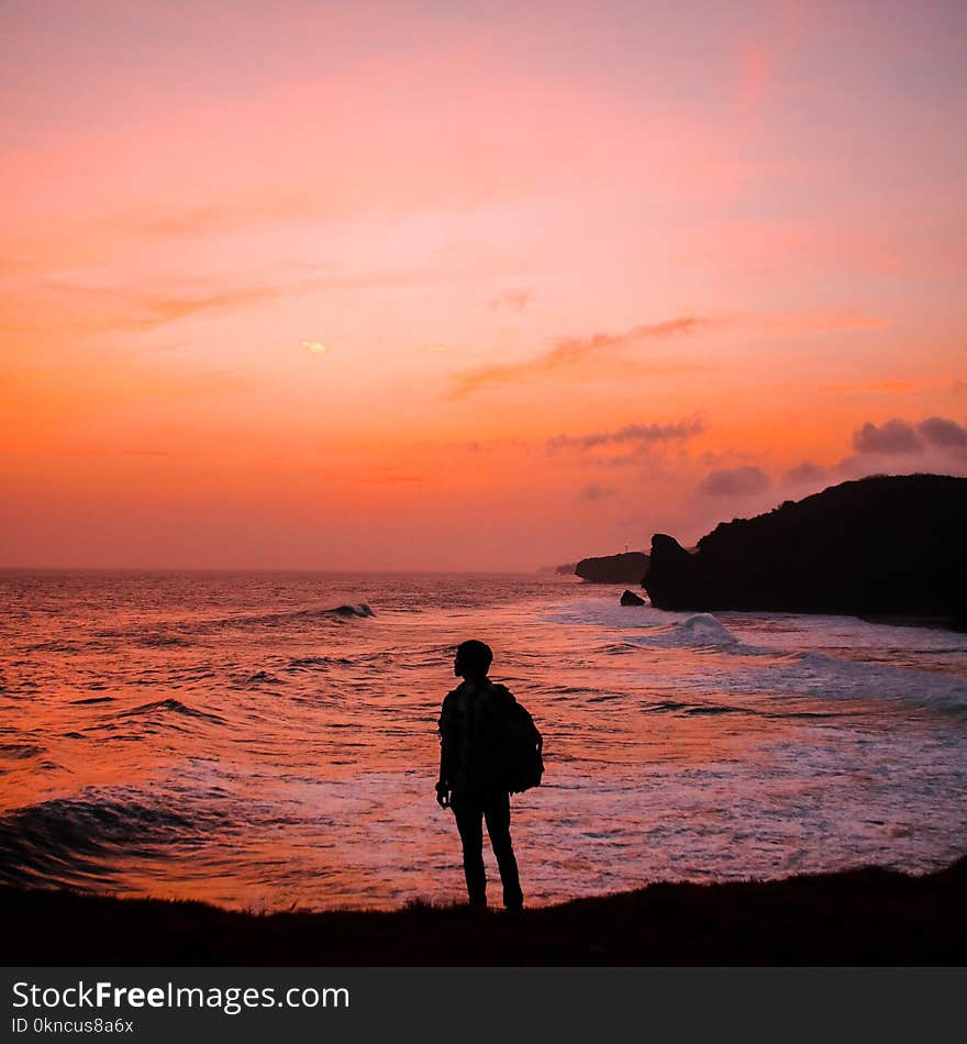 Silhouette Photo of Man With Backpack Standing in Seashore during Golden Hour