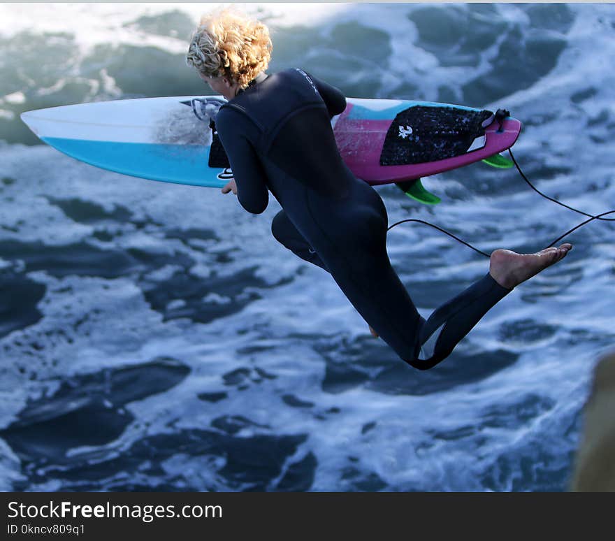 Woman With Surfboard Jumping to Body of Water