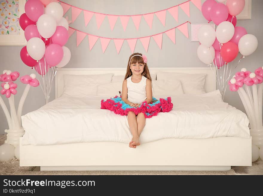 Cute girl sitting on bed in room decorated