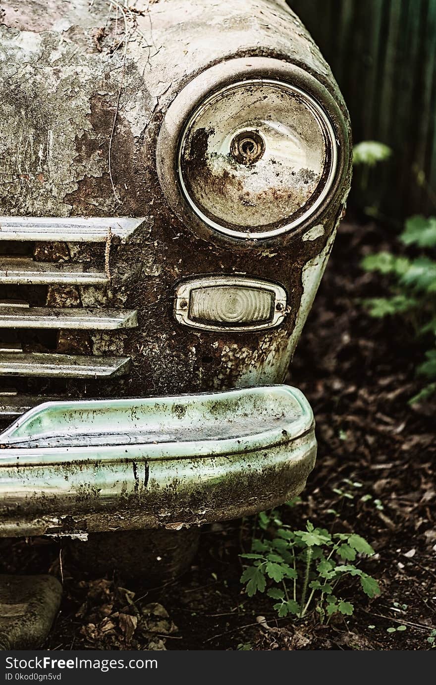 An old rusty abandoned car outdoors in the woods. broken car headlight close-up. An old rusty abandoned car outdoors in the woods. broken car headlight close-up