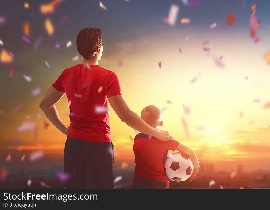 Cute little child dreaming of becoming a soccer player. Boy with men playing football on sunset. Family sport. Cute little child dreaming of becoming a soccer player. Boy with men playing football on sunset. Family sport.