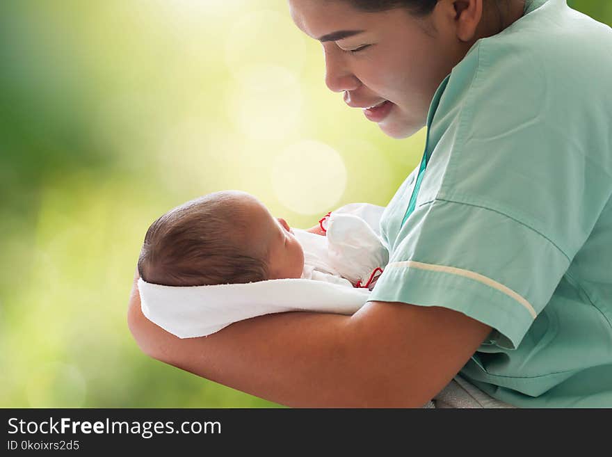 Mother Holding Newborn Infant Baby Girl In Arm On Blurred Bokeh