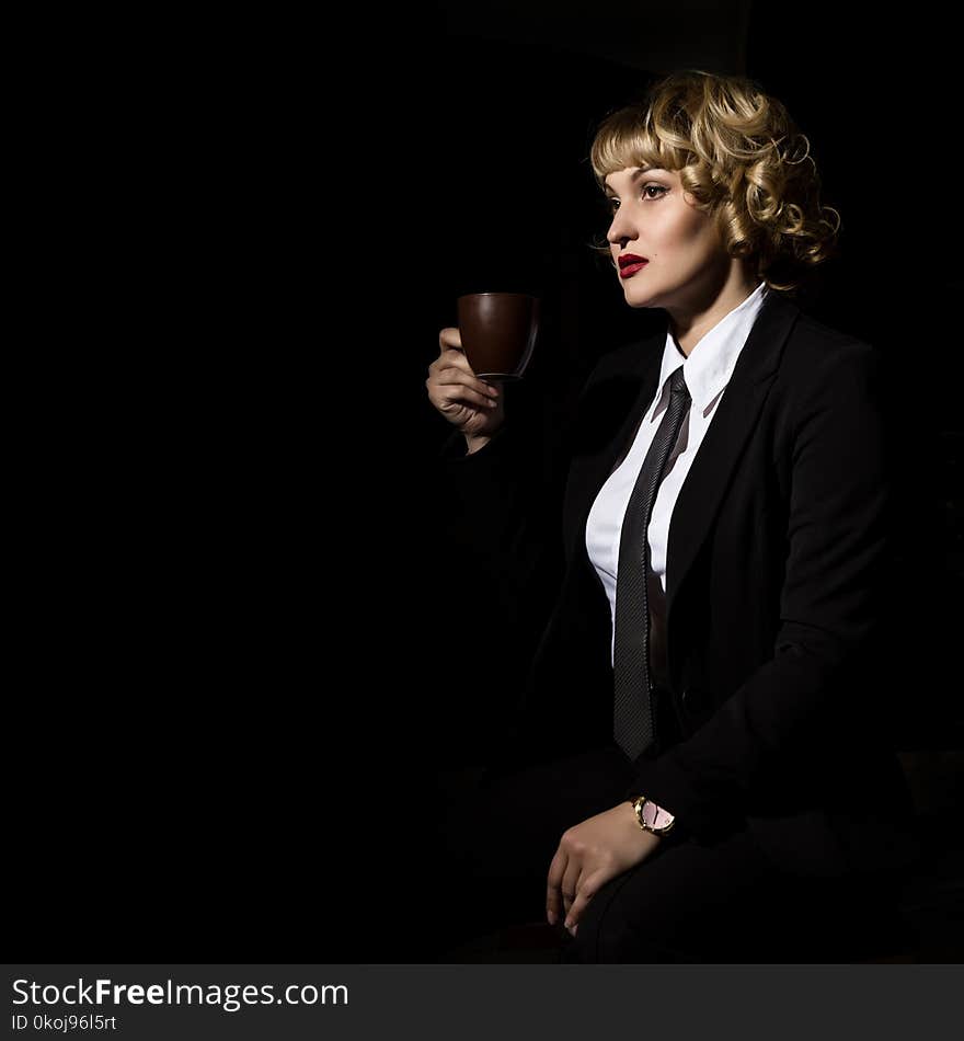 Businesswoman with cup of coffee on a dark background. girl in a business suit. free space for your text