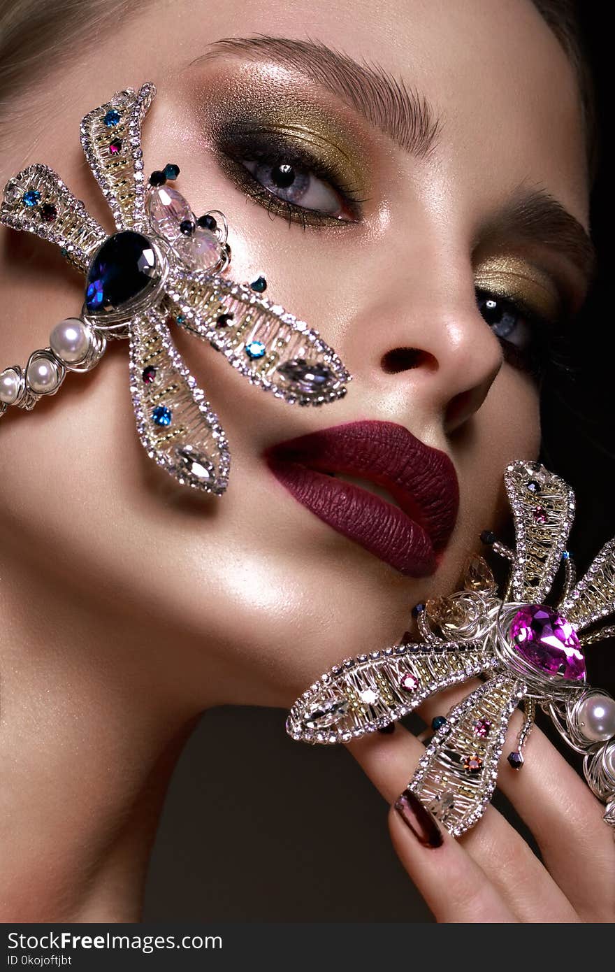 Beautiful blonde girl with curls, bright make-up and designer accessories. Beauty face. Photo taken in the studio.