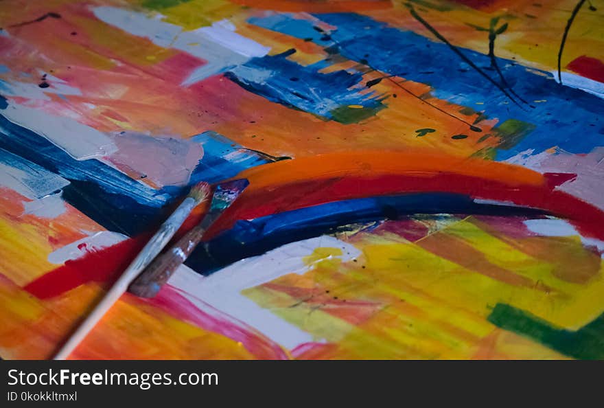 Two Paintbrushes on Multicolored Abstract Painting