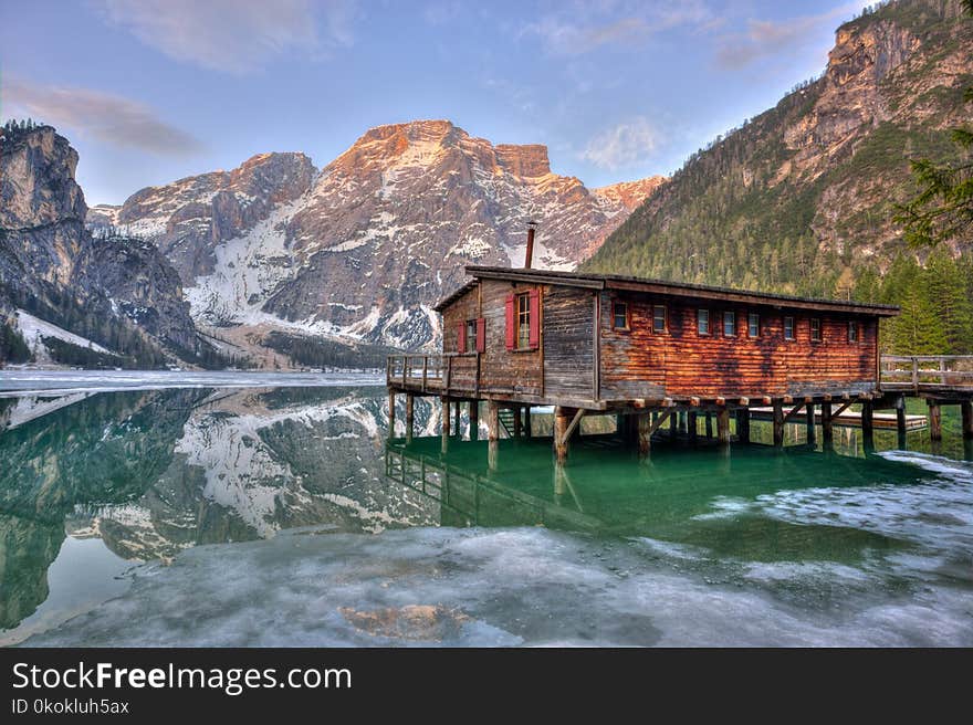 Shack On Body Of Water Surrounded By Mountains