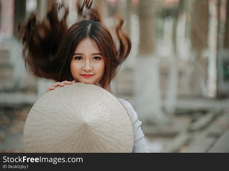 Selective Photography of Woman Holding Conical Hat