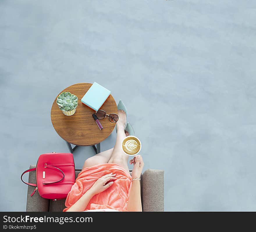 Woman Wearing Peach Skirt Sitting on Sofa Chair Holding a Cup of Coffee