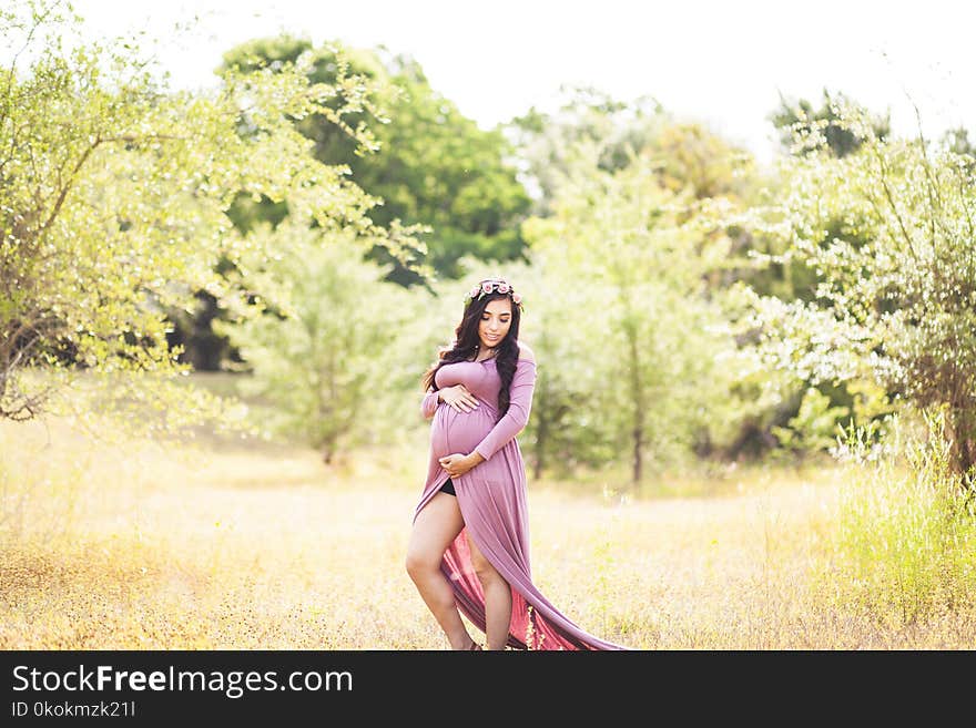 Woman Standing On Grass Field Surrounded With Trees