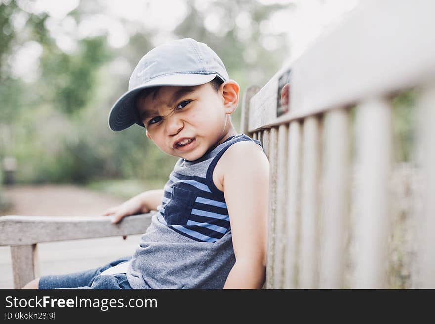 Shallow Focus Photography Of A Boy Sitting On Bench