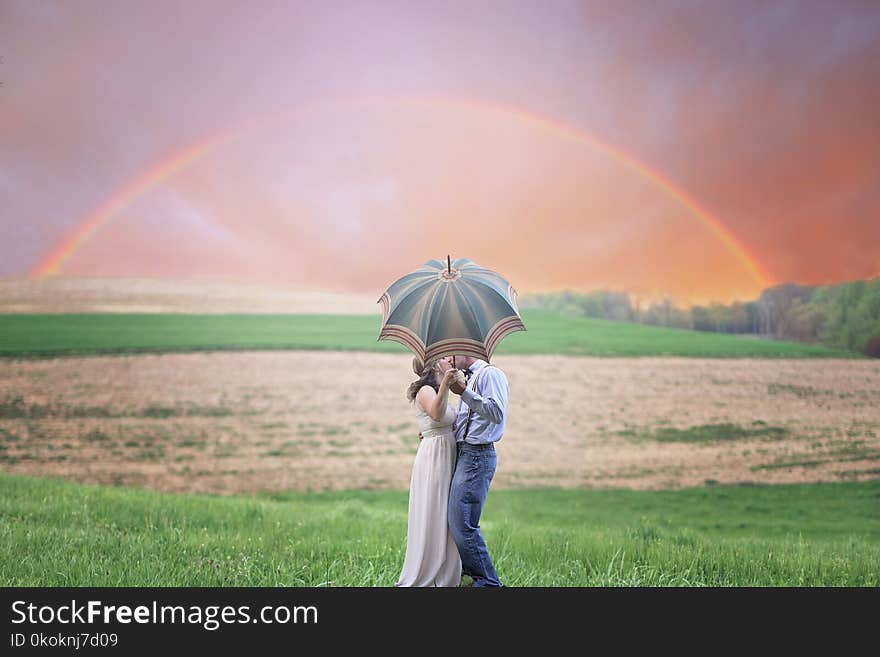 Photo of Couple Holding Umbrella While Kissing