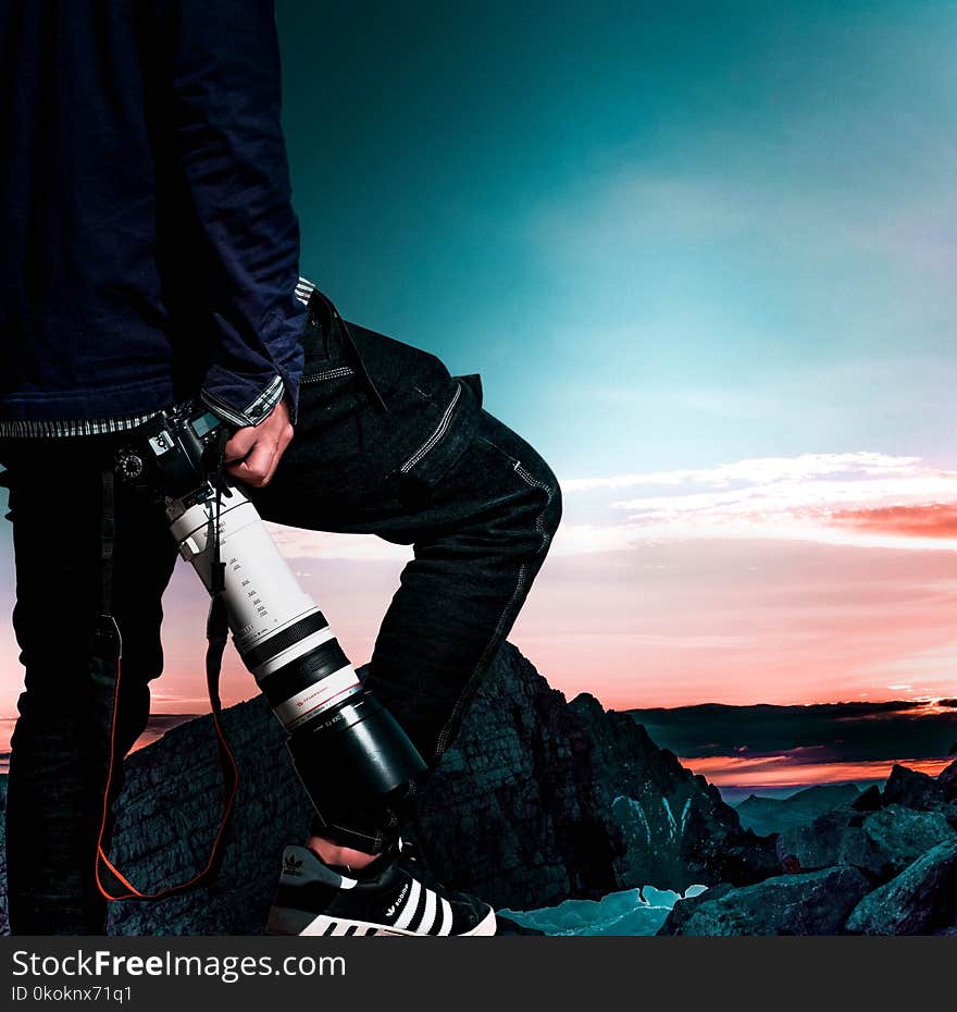 Man Wearing Black Bomber Jacket and Denim Jeans Holding Dslr Camera