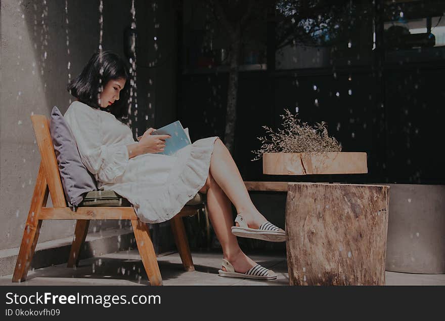 Photography of a Sitting on Chair While Reading Book