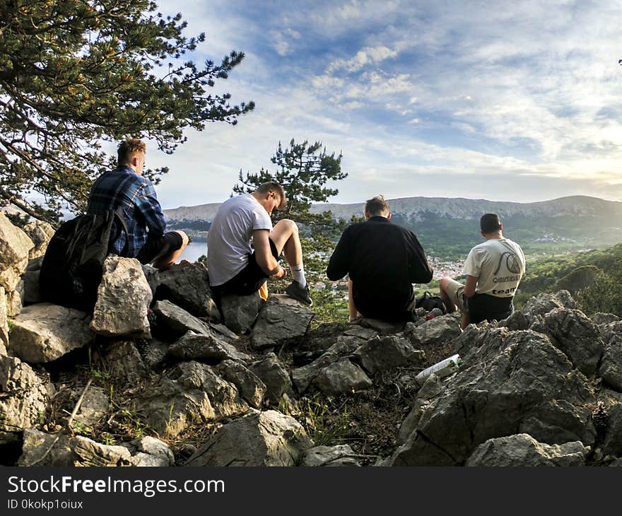 Four Men Seated on Rocks Facing Mountain