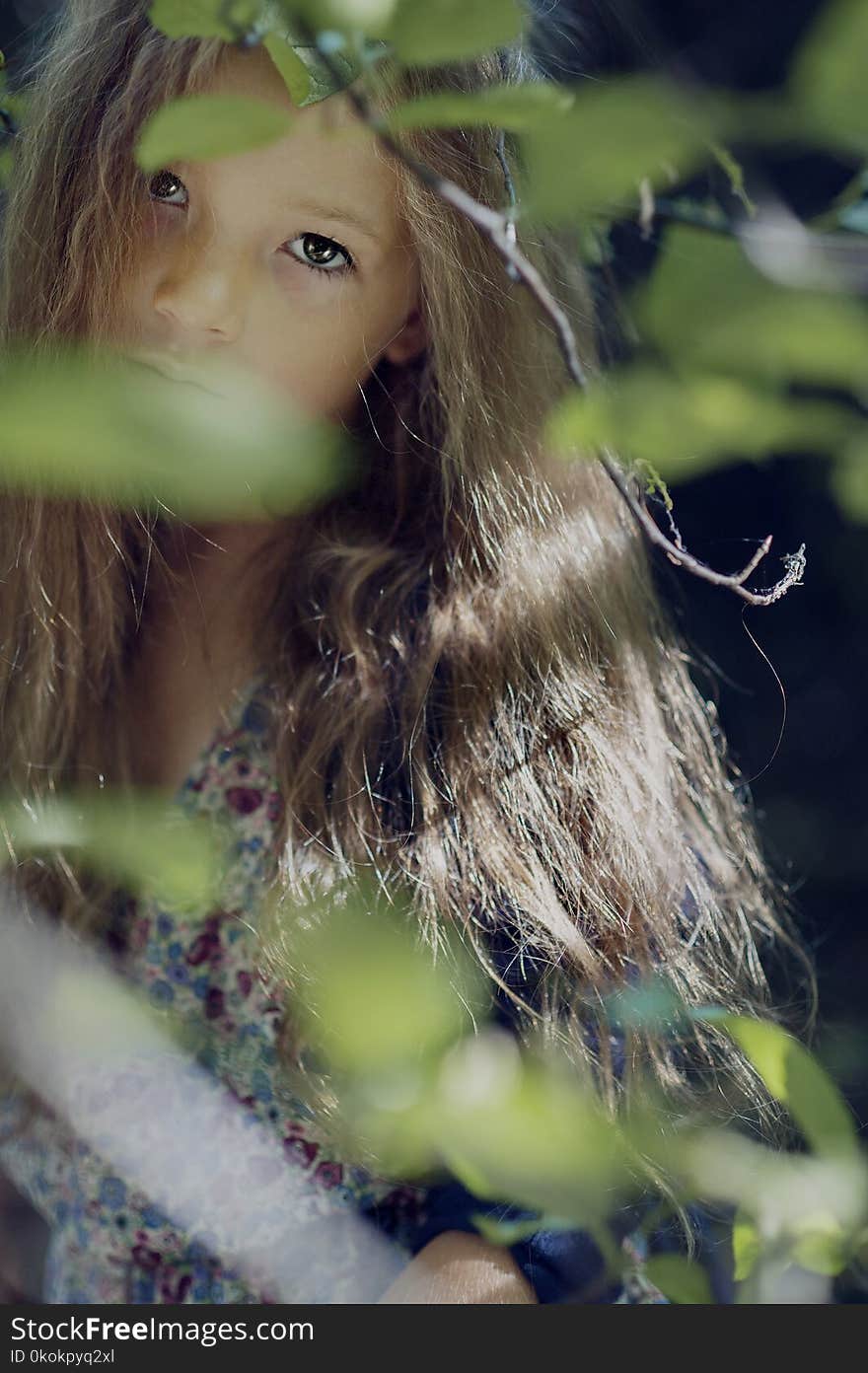 Woman Wearing Multicolored Floral Top Behind Green Leaf Plant