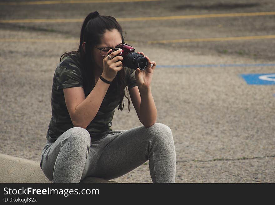 Woman in Gray Pants Sitting While Taking Photo