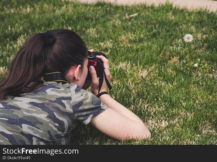 Photo of Woman Taking Photo of Flower on Grass