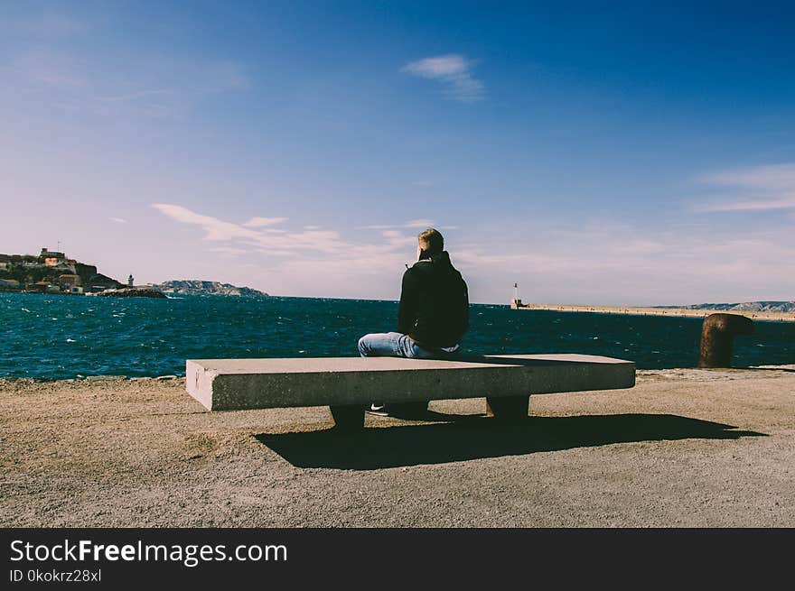 Person Wearing Blue Jeans Sitting on Bench