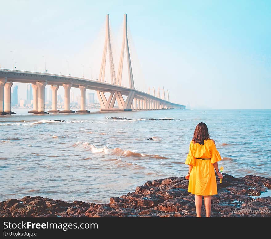 Woman Standing Near Body of Water and Bridge