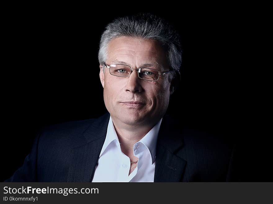 Portrait of a mature gray-haired business man isolated on black. Portrait of a mature gray-haired business man isolated on black.