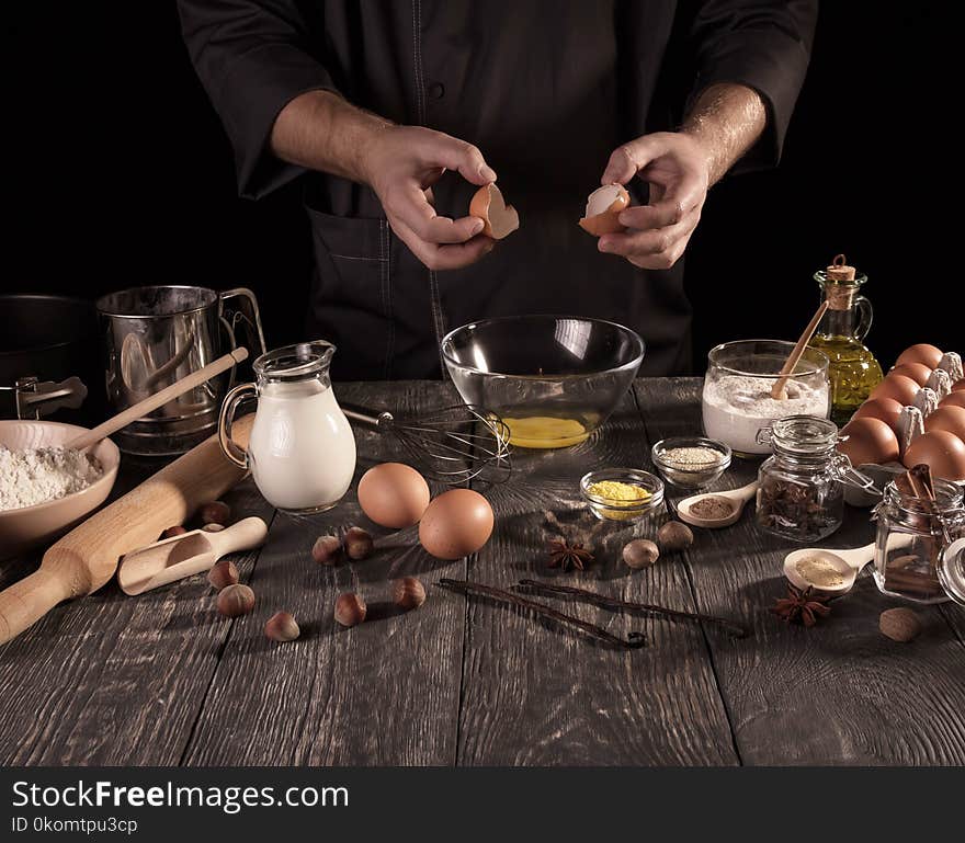 Hands Baker break eggs in glass bowl isolated on black background