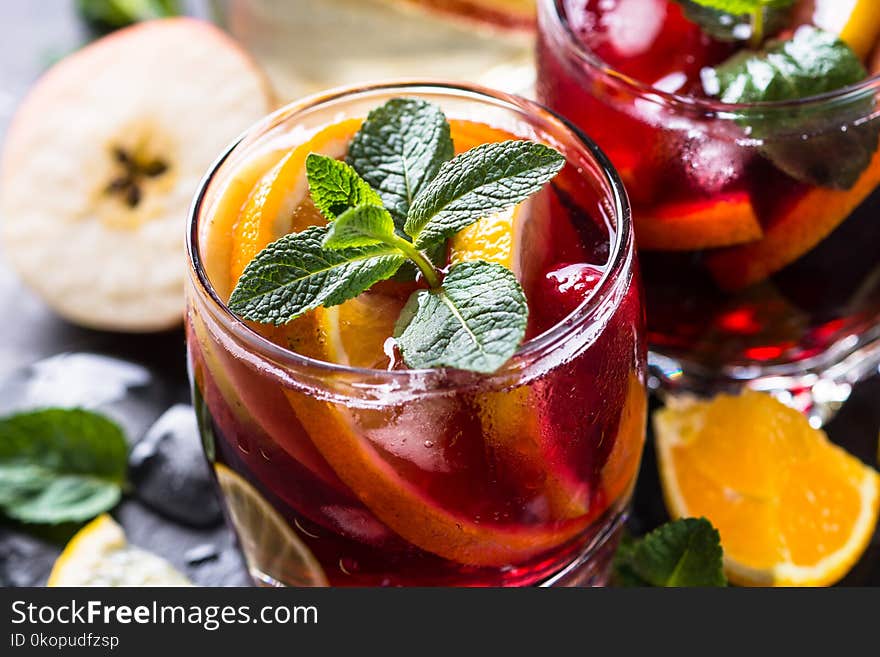 Sangria with fruit, ice and mint in glass. Summer alcohol drink and ingredients. Close up.