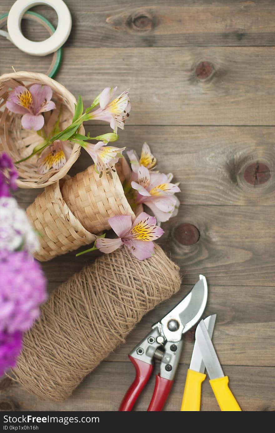 Floristic tools Background. Pink Alstromeria Carnation Flowers on Wooden Background with Garden Floristic Tools and Wire Rustic Floral Board.