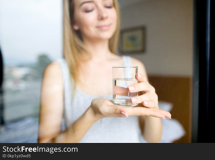 Girl keeping glass of water, blurred background.