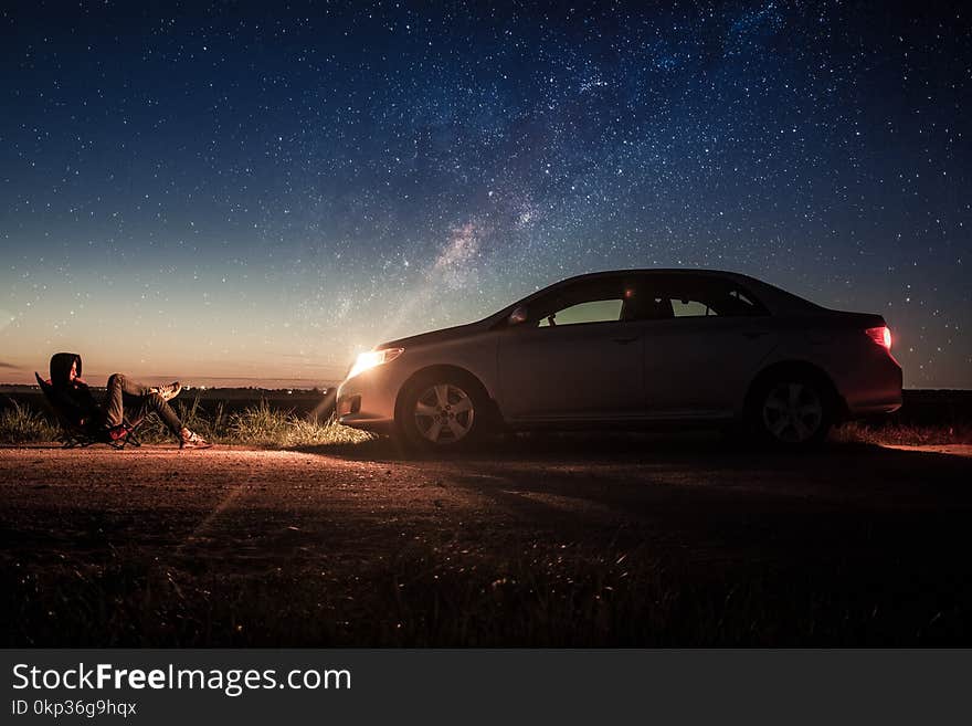 Person Laying in Front of Silver Sedan