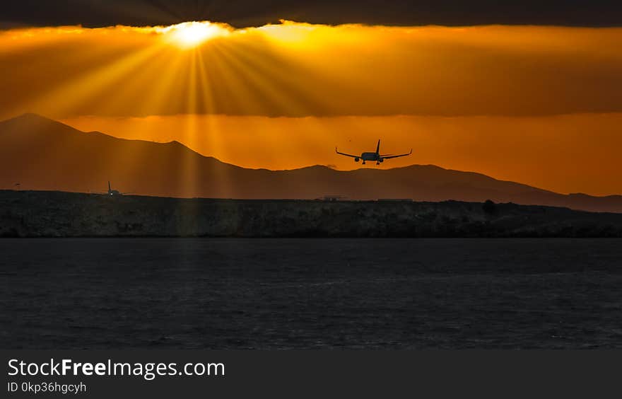 Silhouette of Airplane over Body of Water