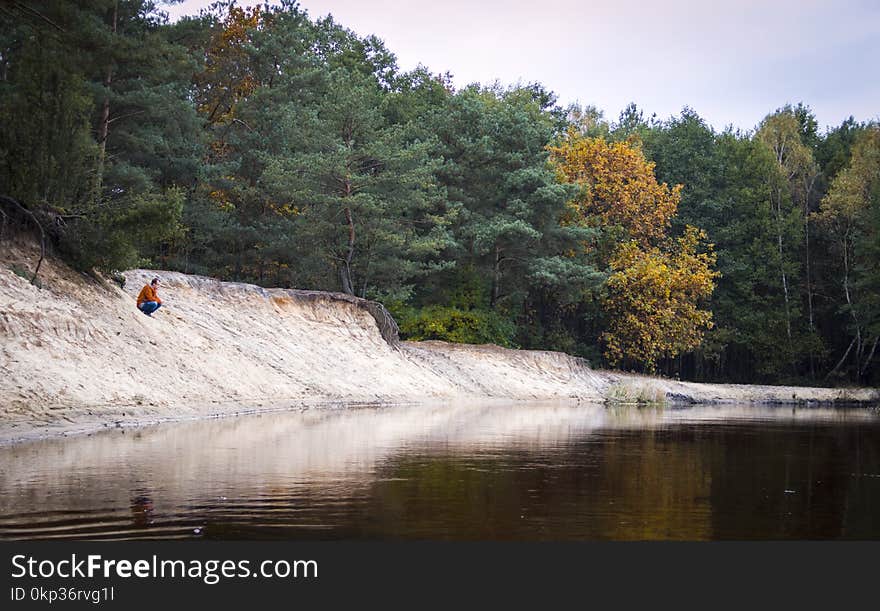 Person Seated Facing Body of Water