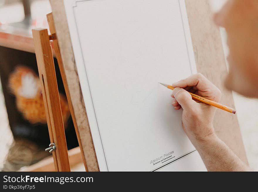 Person Holding Pencil on White Canvas