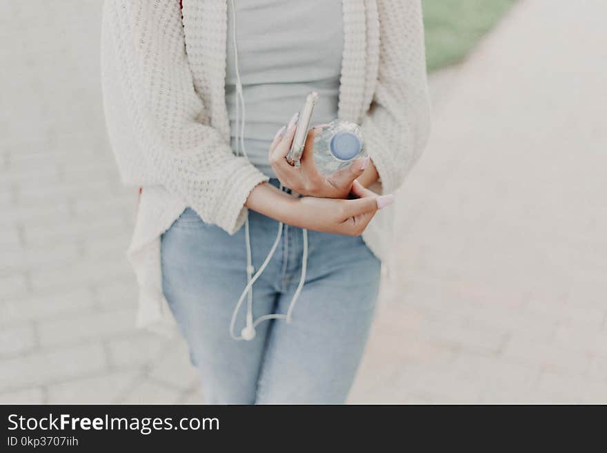 Woman Wearing White Cardigan Holding Plastic Bottle