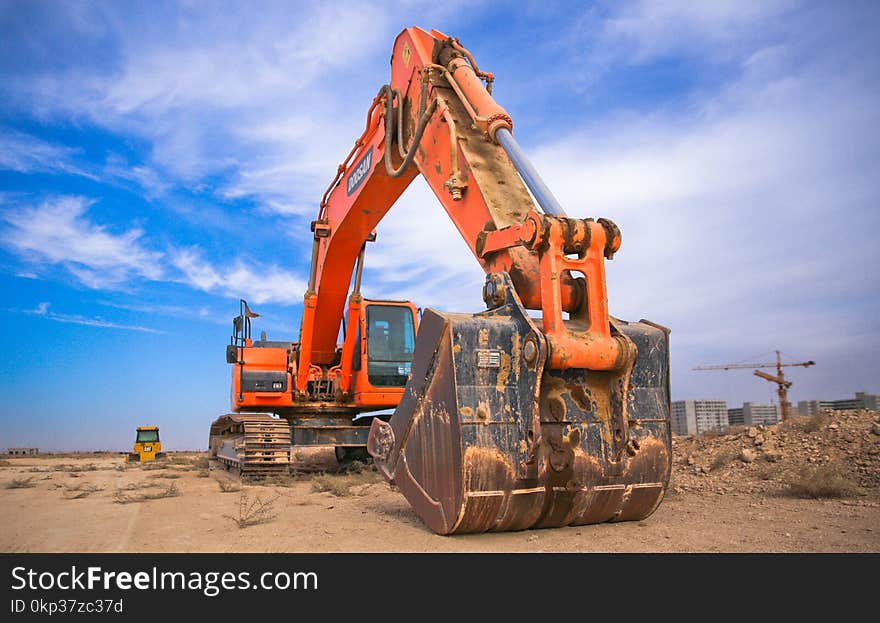 Low Angle Photography of Orange Excavator Under White Clouds