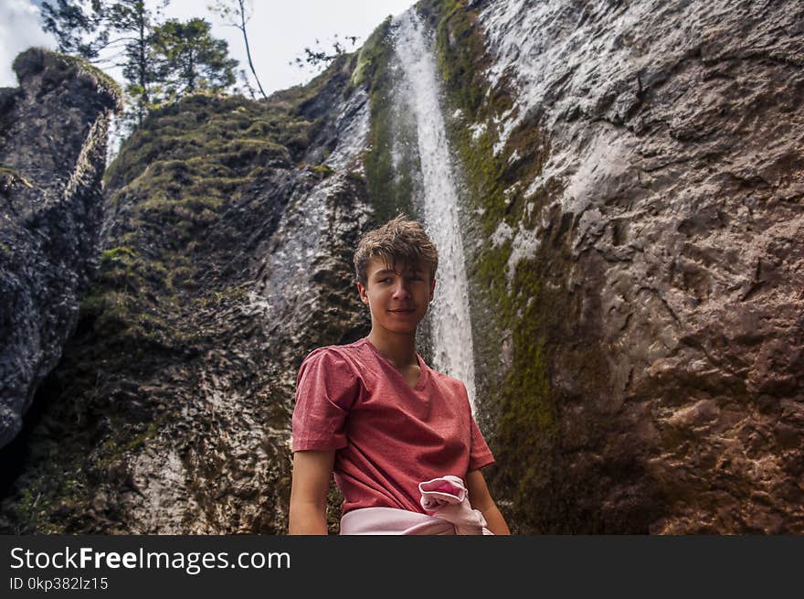 Man Wearing Red Crew-neck Shirt Standing Near Waterfalls