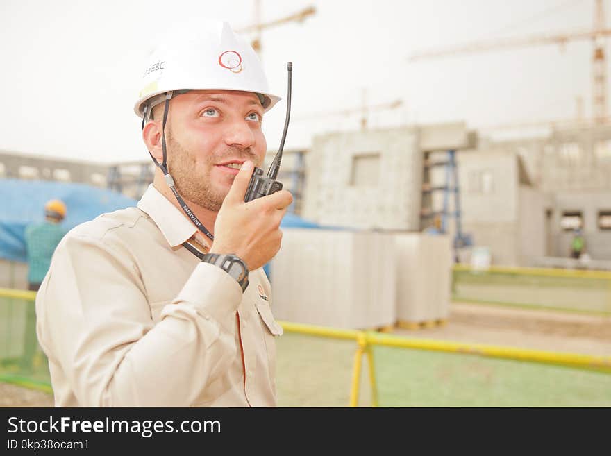 Man Wearing White Hard Hat Holding 2-way Radio