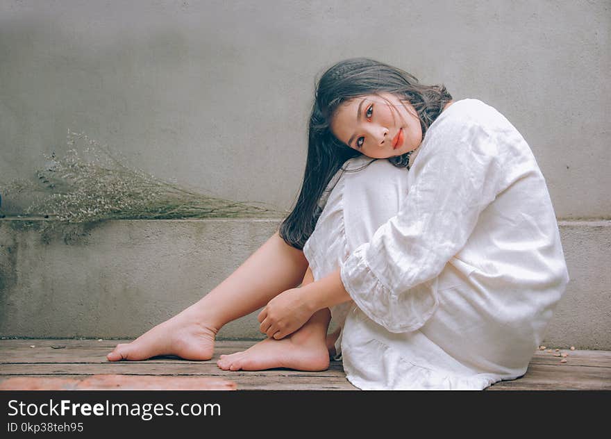 Woman Wearing White Dress Sitting on Wooden Floor