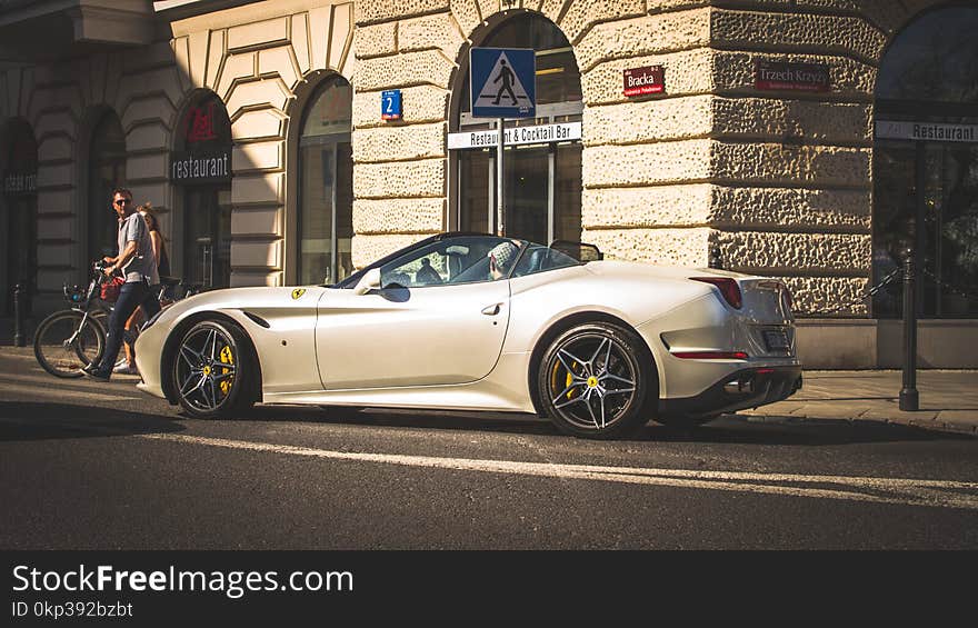 White Coupe Beside Grey Concrete Building