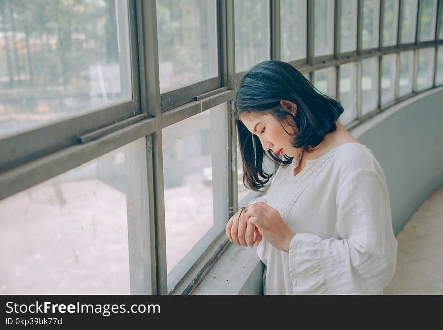 Woman in White Sweater in Front of Window