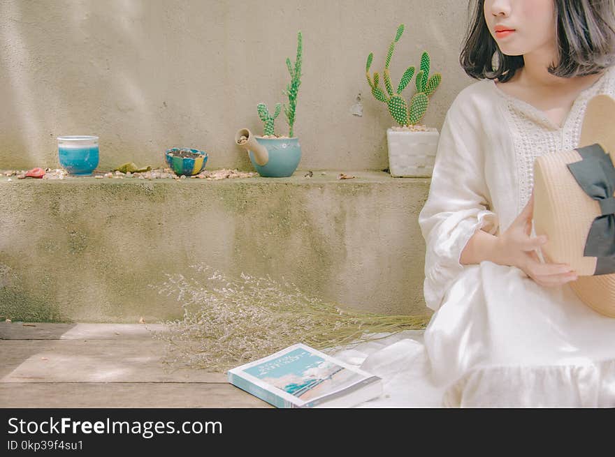 Photography of Woman Sitting Holding Straw Hat