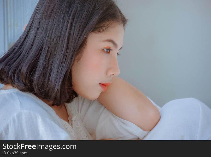 Photo of Woman Wearing White Leaning on Her Elbow