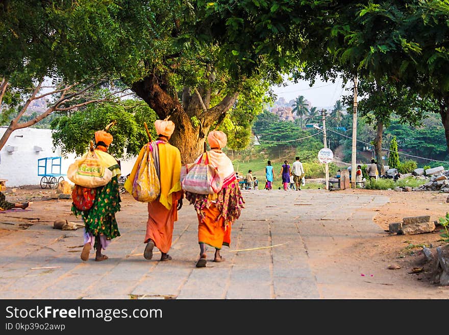 Three Person Walking on Concrete Road