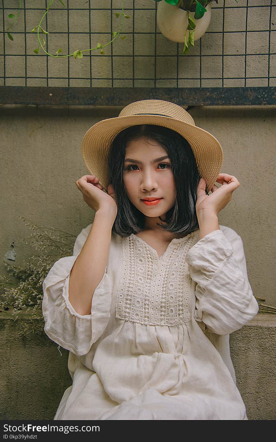 Woman Sitting While Holding Beige Straw Hat