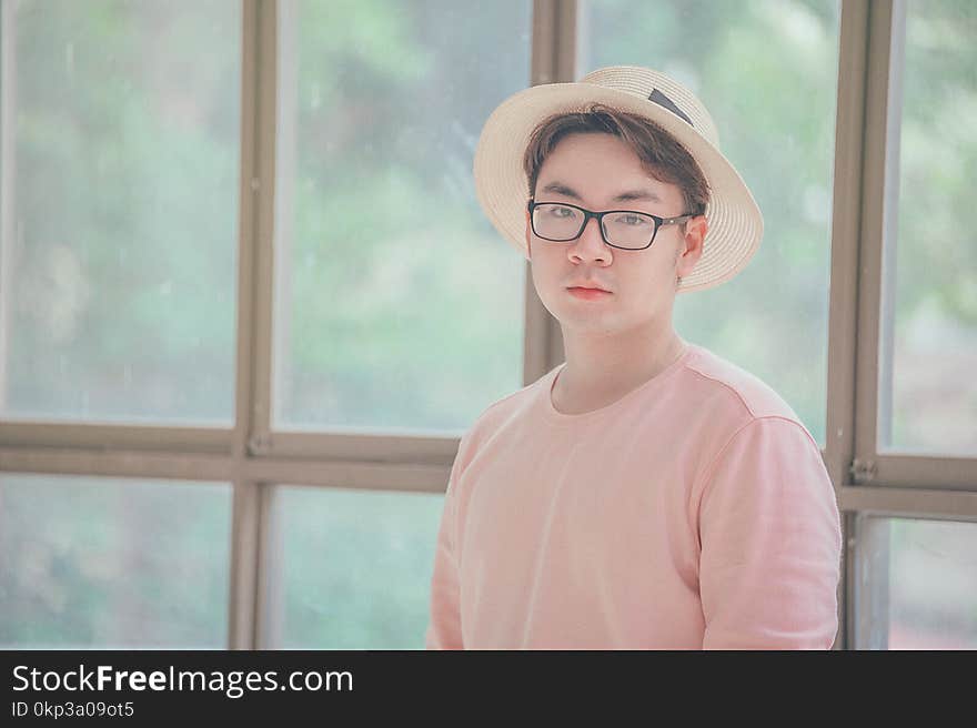 Man Wearing Pink Top Standing Near Glass Panel