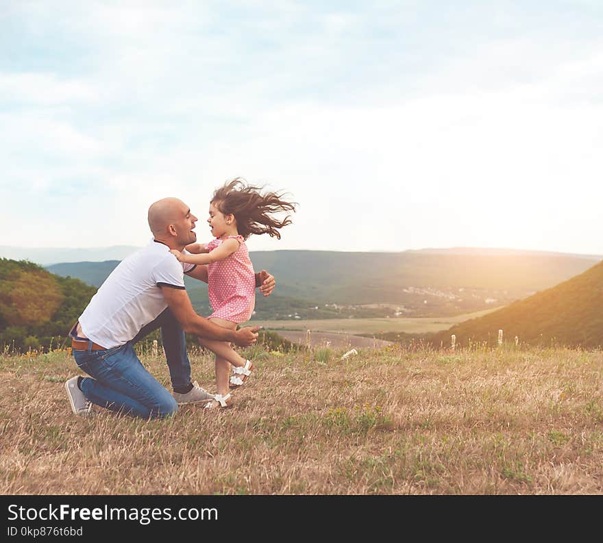 Father holds his pretty daughter and they are huging on summer sunset. Lovely emotions, happy family concept